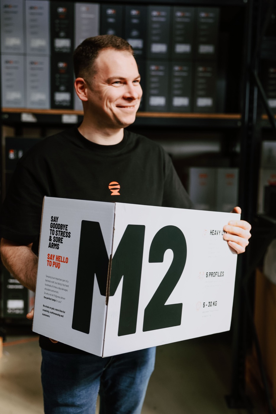 Kolega Flatwhite drží krabici Puq Press M2 ve skladu kávového vybavení